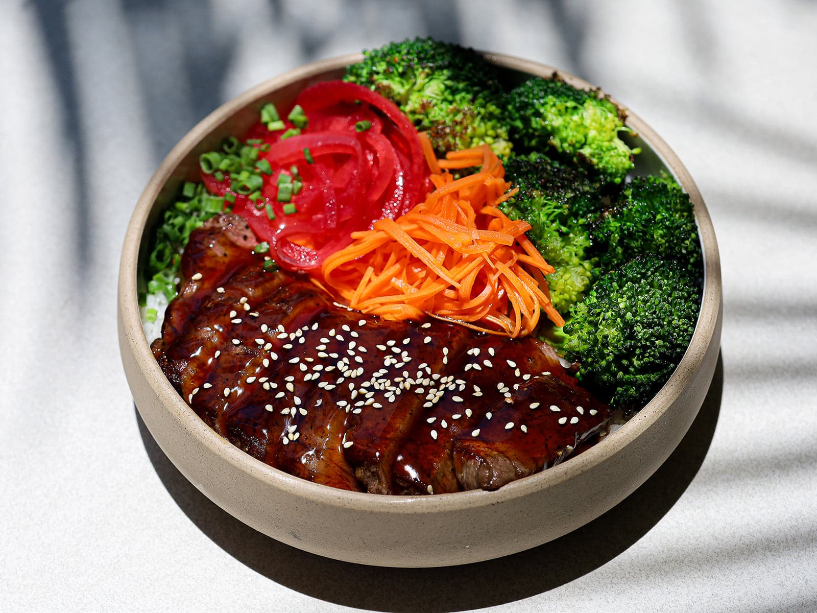 Teriyaki beef bowl with broccoli, pickled onion and carrot